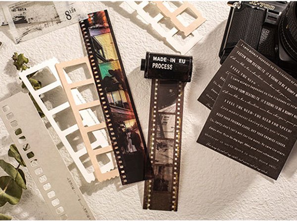 Film strip scrapbook embellishments and decorative paper cards arranged with a vintage camera