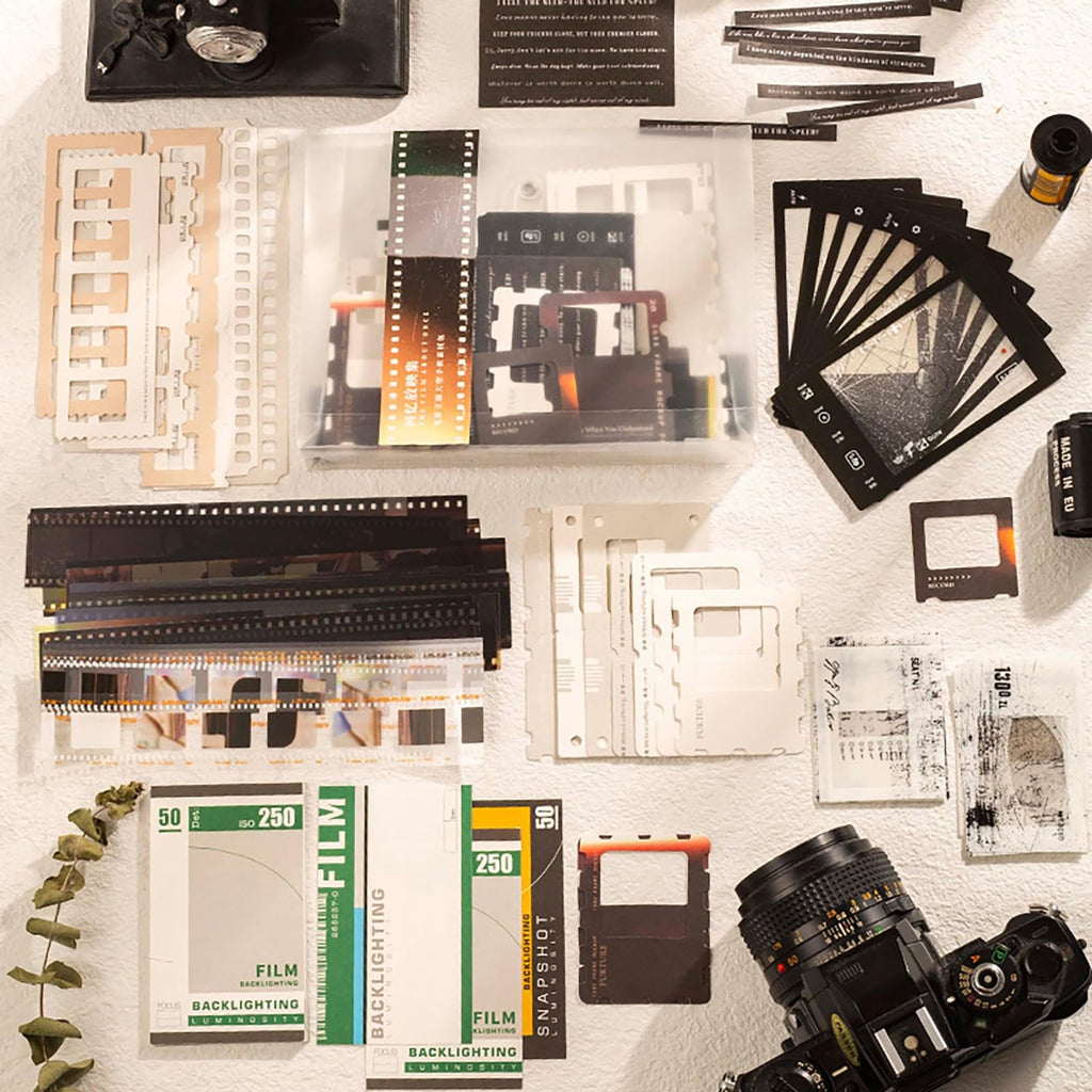 Flat lay of film scrapbook paper kit contents including film strips, memo cards, stickers, and camera parts.