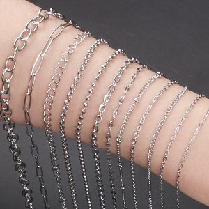 Various styles of stainless steel jewelry chains displayed on an arm, showing different link types like oval and ball.