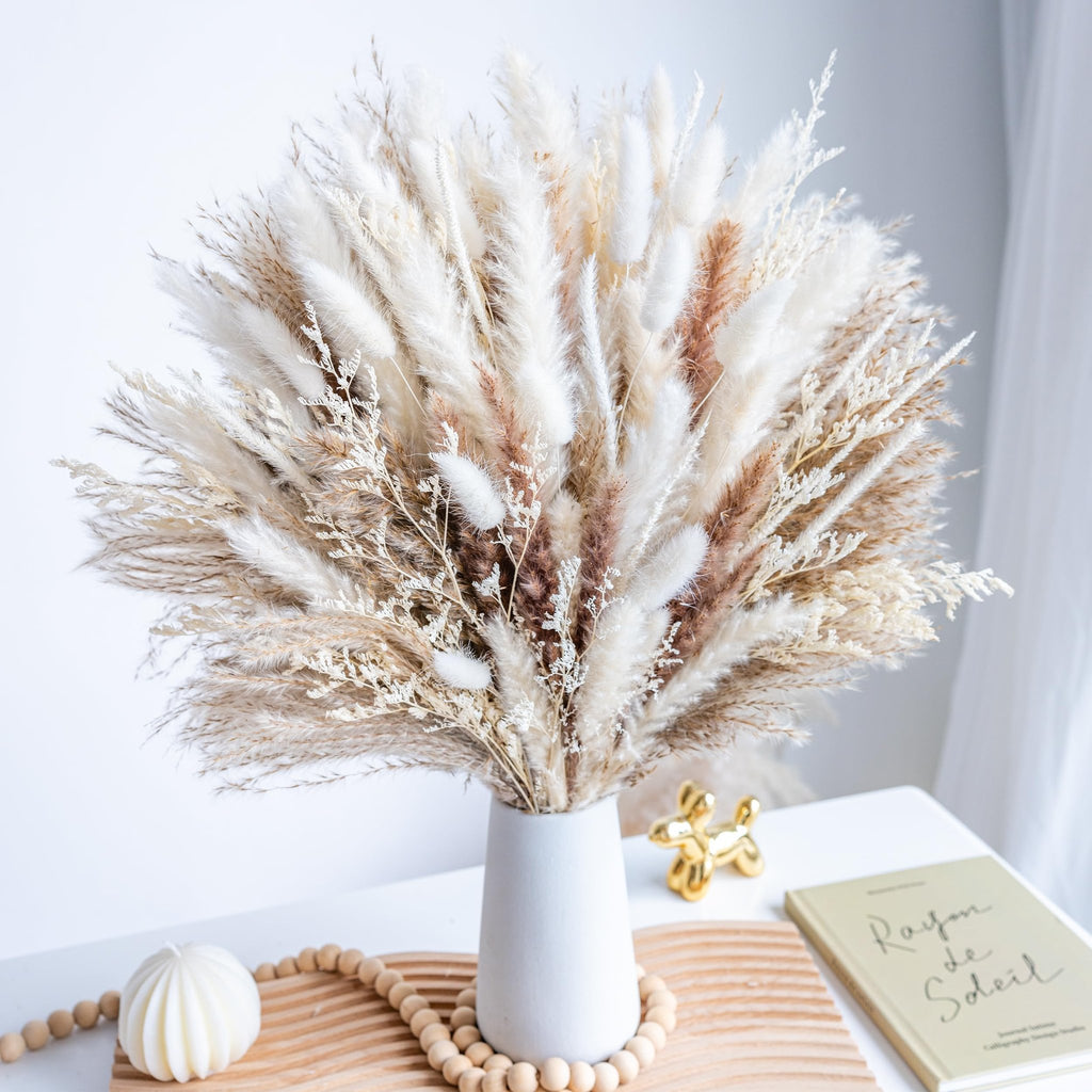 Boho dried pampas grass bouquet in a white vase on a table with decorative items
