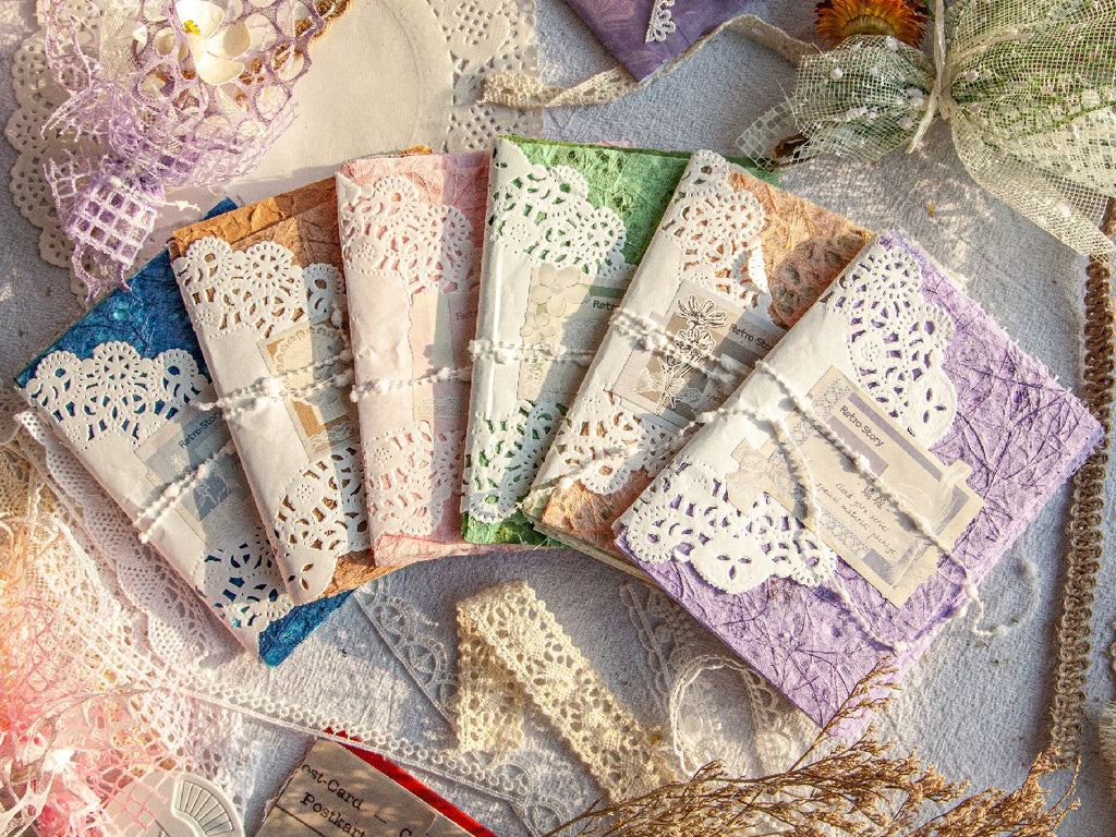 Assortment of textured scrapbook paper packs with lace trim, arranged in a fan shape on a textured surface.
