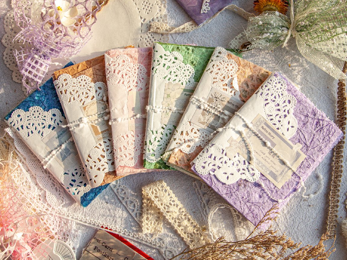 Assortment of textured scrapbook paper packs with lace trim, arranged in a fan shape on a textured surface.