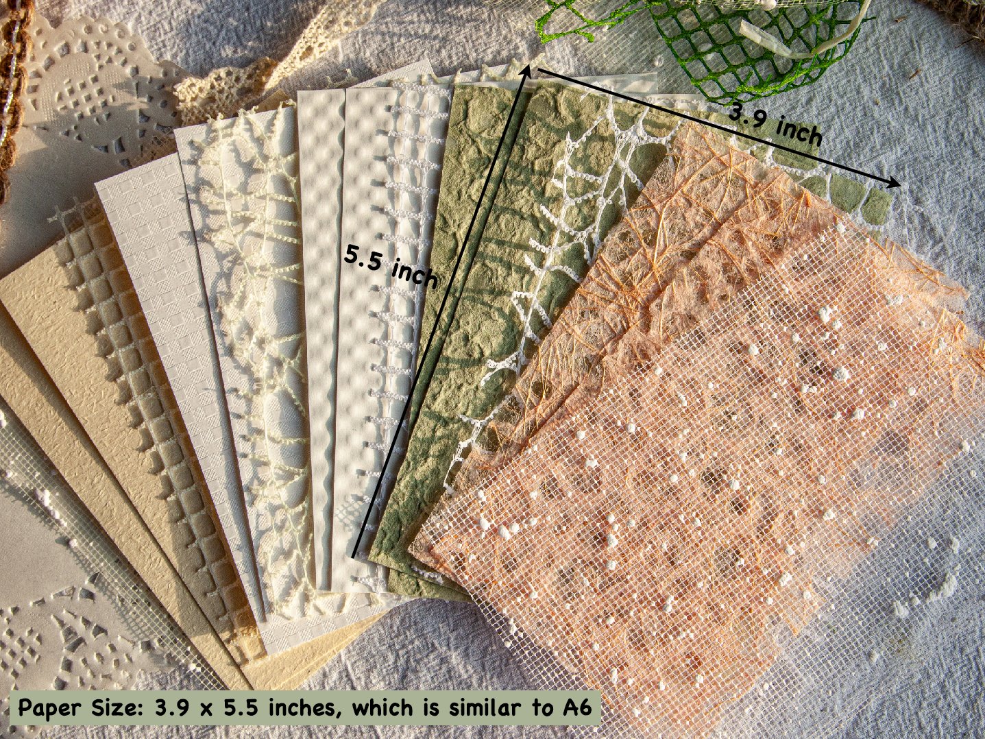 Assortment of textured scrapbook papers and mesh fabrics fanned out, showing various patterns and colors, with dimensions indicated.