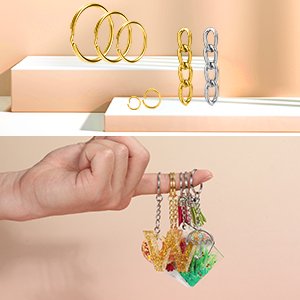 Gold and silver keychain hardware and finished resin keychains with charms held by a hand.