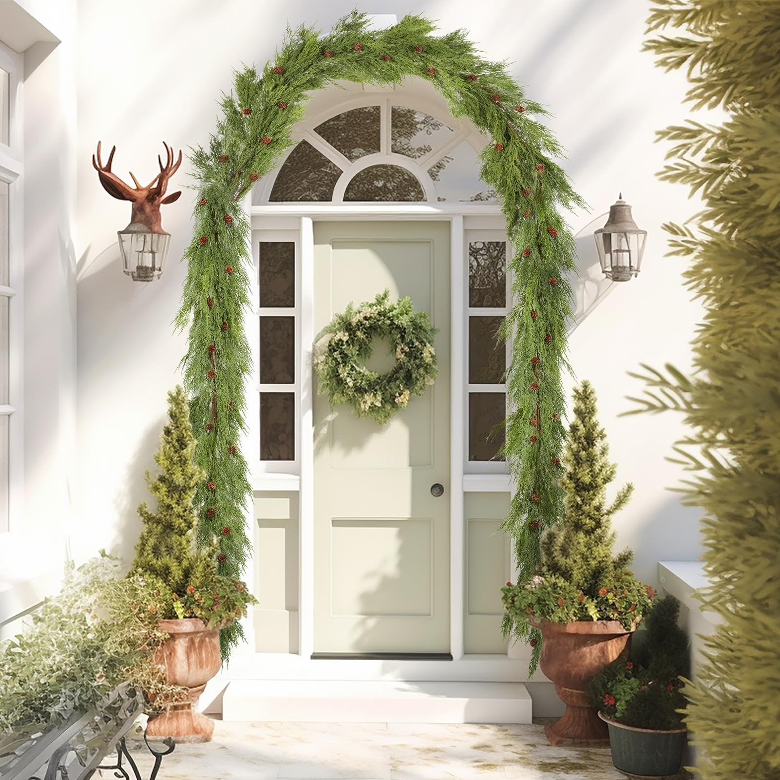 Front door decorated with a pine cone garland and wreath, flanked by potted trees.