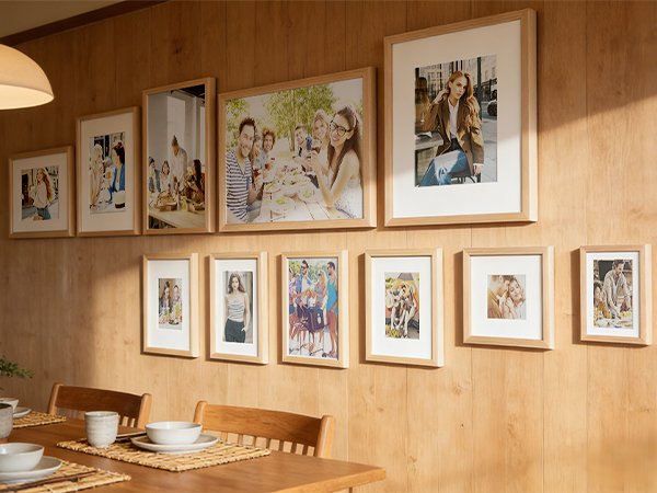Gallery wall of natural wood picture frames displaying various photos of people and gatherings on a wood-paneled wall.
