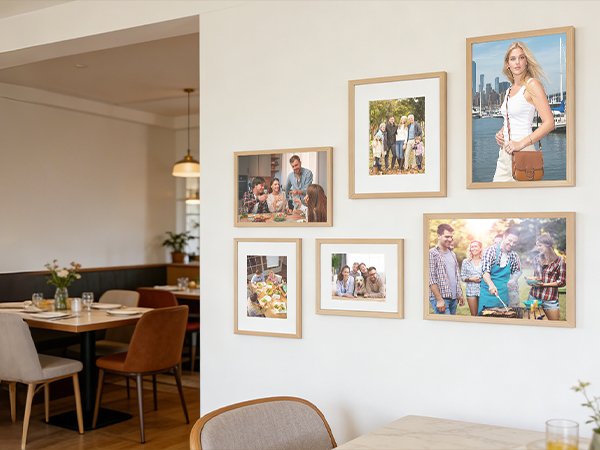 Several framed photos of families and friends displayed on a wall in a dining area.