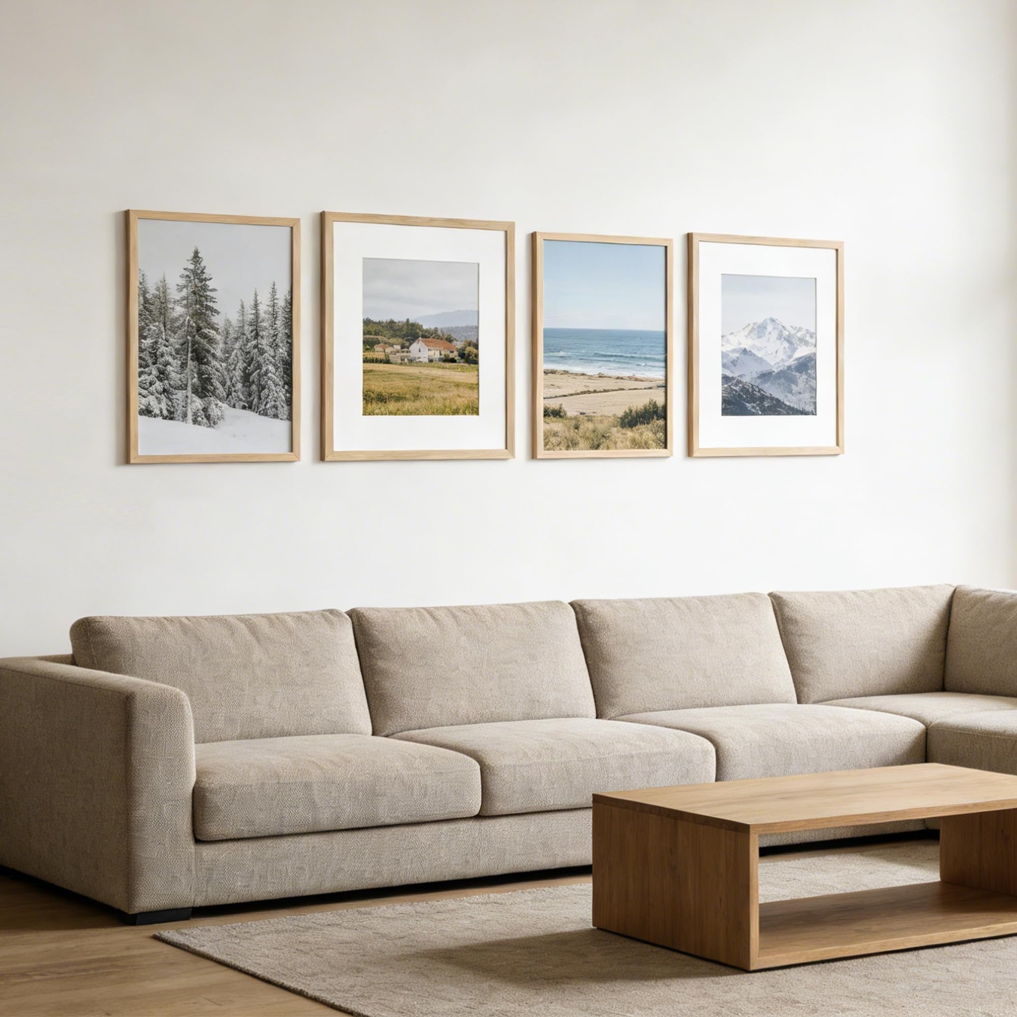 Four framed landscape prints displayed on a white wall above a sectional sofa and coffee table.