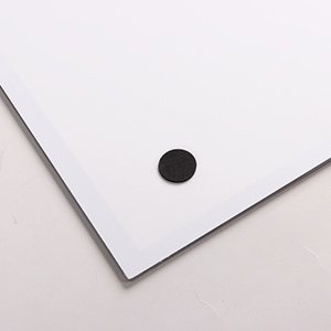 Close-up of a white LED light pad with a black circular foot on a white surface.