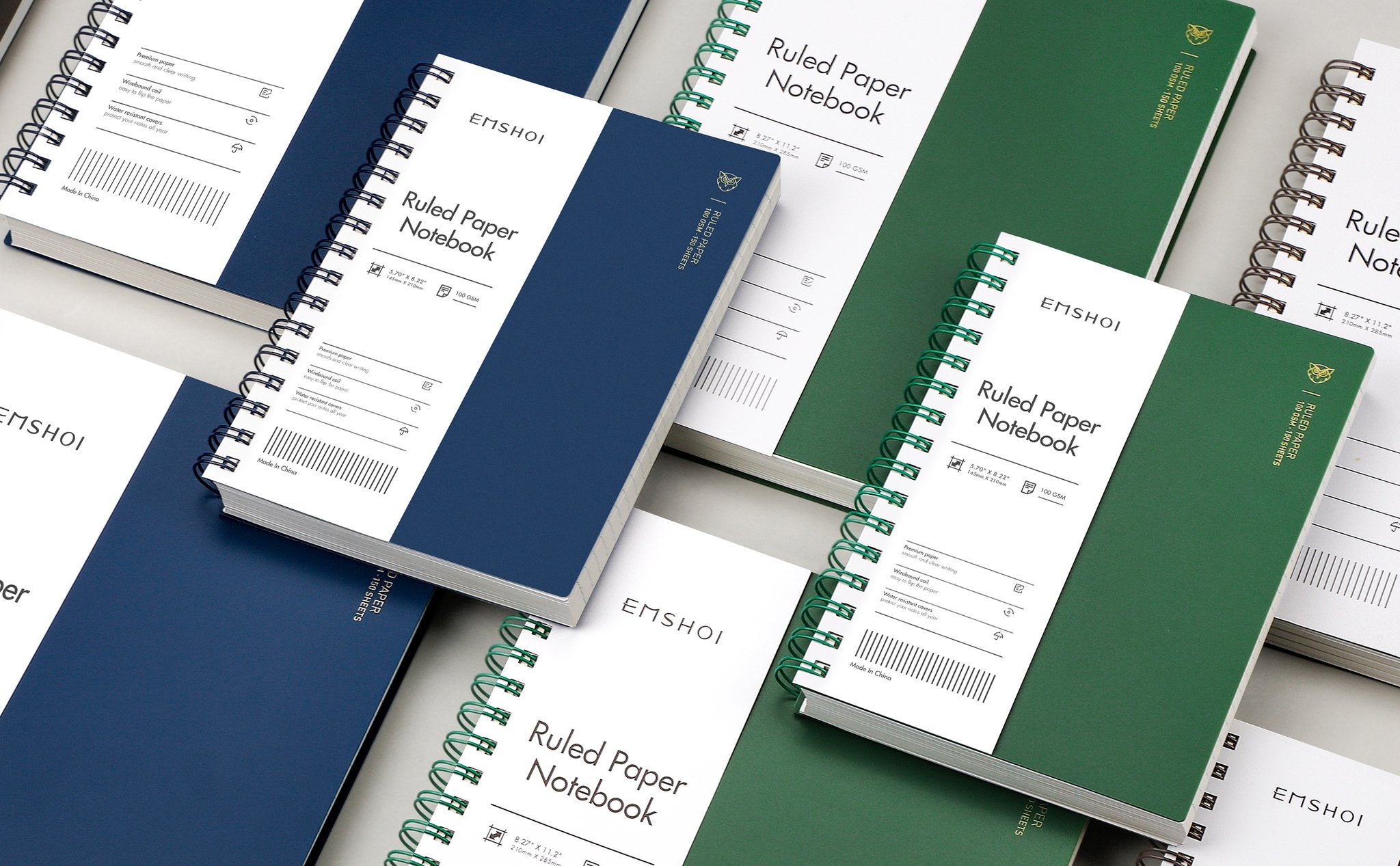 Several spiral-bound notebooks in green and navy blue, some open to show ruled paper and features.
