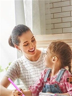 Mother and daughter smiling while doing a craft project together at a table
