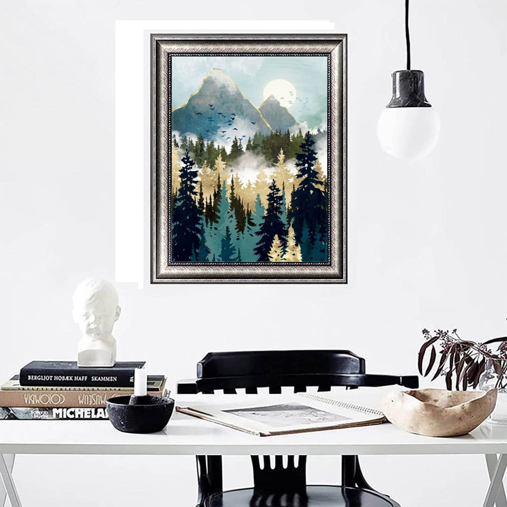 Framed abstract mountain forest landscape painting hanging on a white wall above a desk with books and a bust.