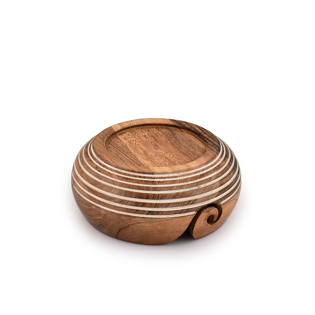Wooden yarn bowl with carved spiral detail and concentric rings, shown from a low angle on a white background.