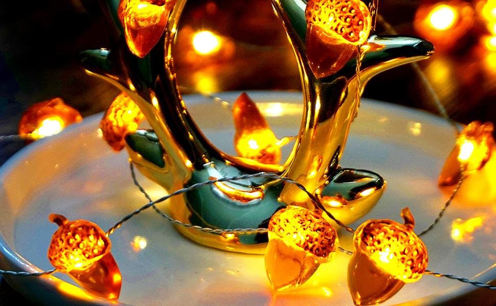 Close-up of acorn-shaped fairy lights on a decorative gold stand, illuminated with warm yellow light.