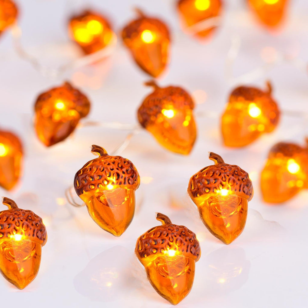 Close-up of illuminated acorn-shaped string lights on a white background, showing multiple lights in focus and out of focus.