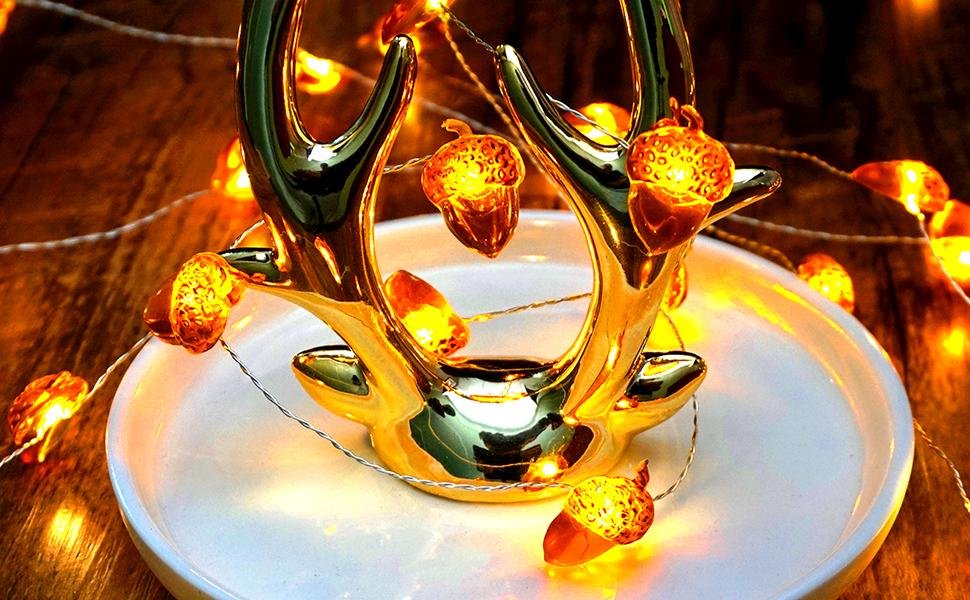 Golden antler decoration with acorn-shaped string lights on a white plate