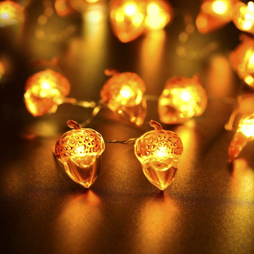 Close-up of illuminated acorn-shaped string lights on a dark, reflective surface.