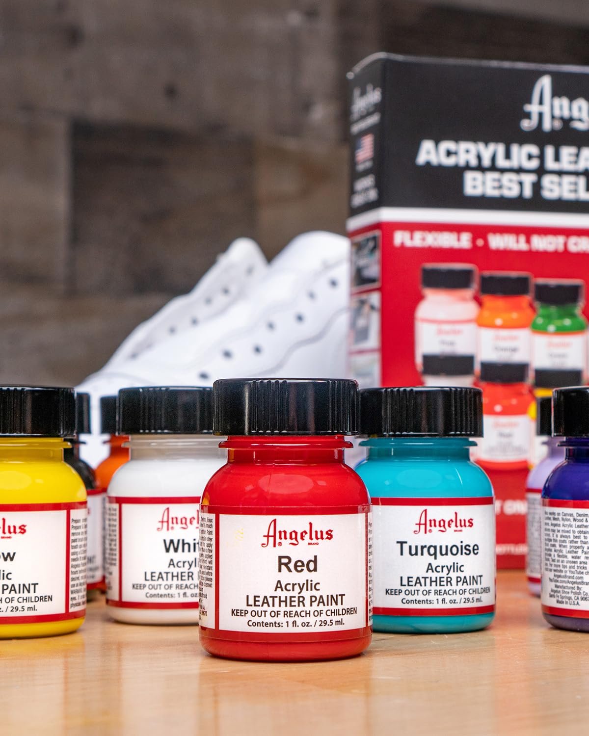 Assortment of acrylic leather paint bottles in various colors, with a white sneaker and product box in the background.