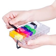 Hands holding open clear paint palette box with 24 deep wells filled with colorful paints, using a black tool to mix paint.