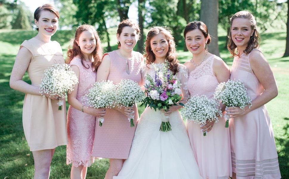 Bride and bridesmaids holding bouquets of white baby's breath flowers outdoors