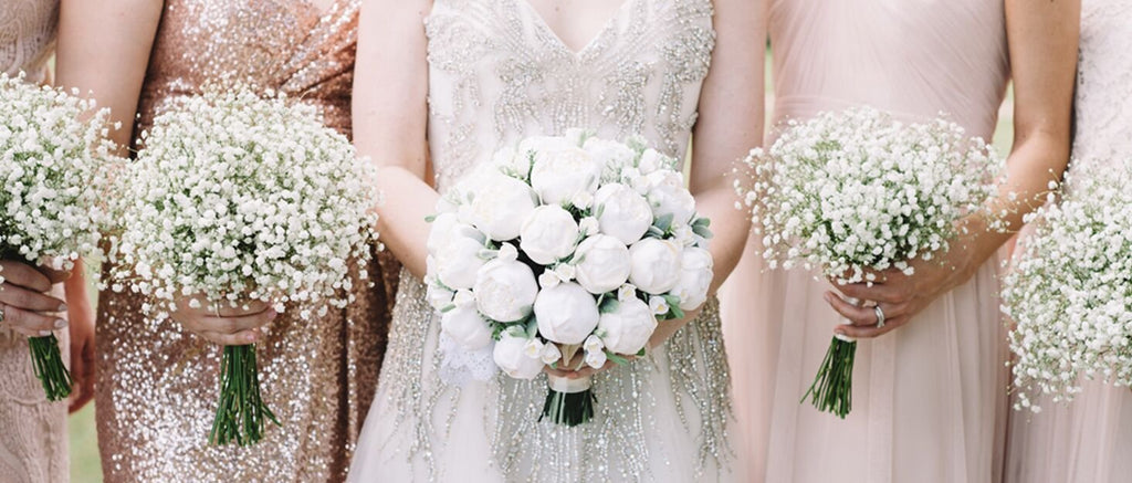 Bride and bridesmaids holding bouquets of white flowers at a wedding ceremony