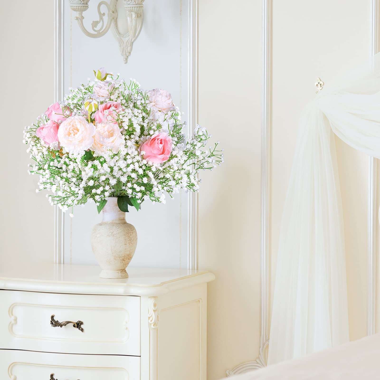 Bouquet of artificial pink and white roses with baby's breath in a textured vase on a dresser