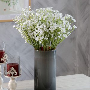 Artificial baby's breath flowers in a gray vase with red candles in the foreground.