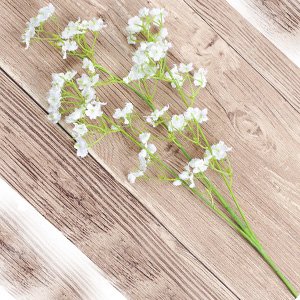 Artificial baby's breath flower stems with white blossoms on a wooden background