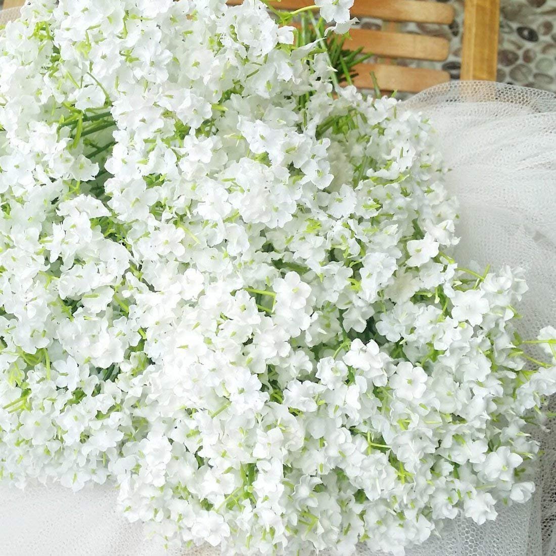 Close-up of a bouquet of artificial white baby's breath flowers with green stems, draped with white tulle.