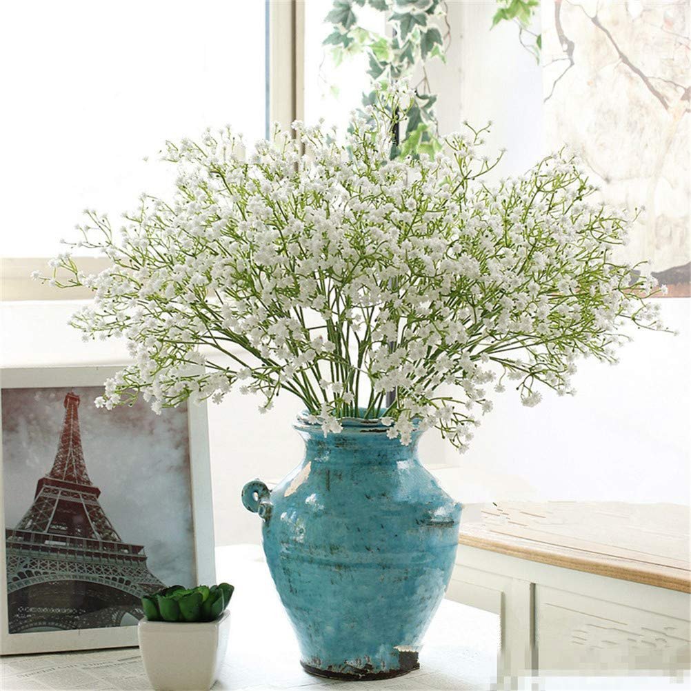 Artificial baby's breath flowers in a blue vase with a framed Eiffel Tower picture and a small succulent plant.
