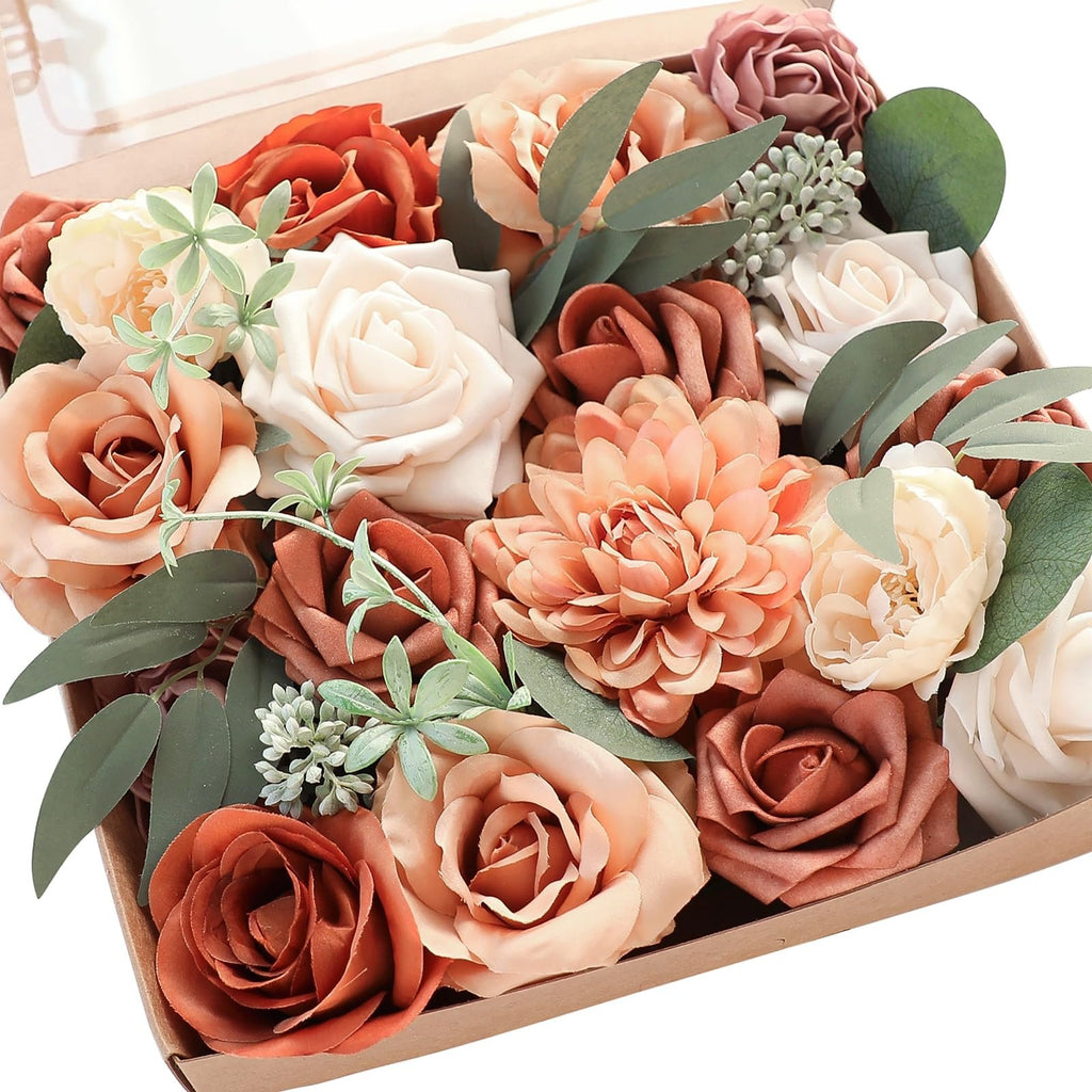 Box of assorted artificial flowers in terracotta, champagne, amber, cream, and burnt orange colors with green leaves.