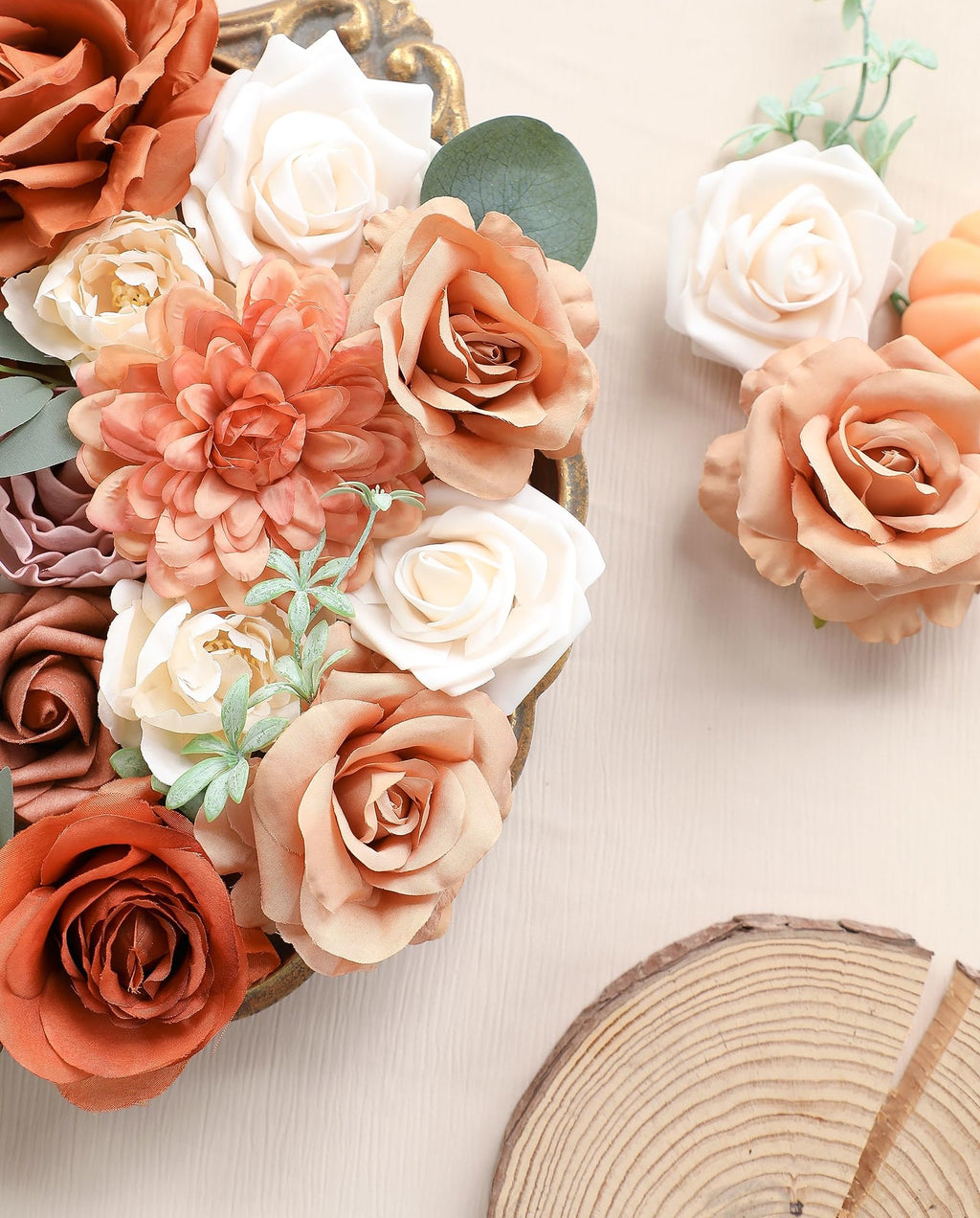 Assortment of artificial flowers in terracotta, champagne, amber, and cream colors arranged in a decorative gold tray.