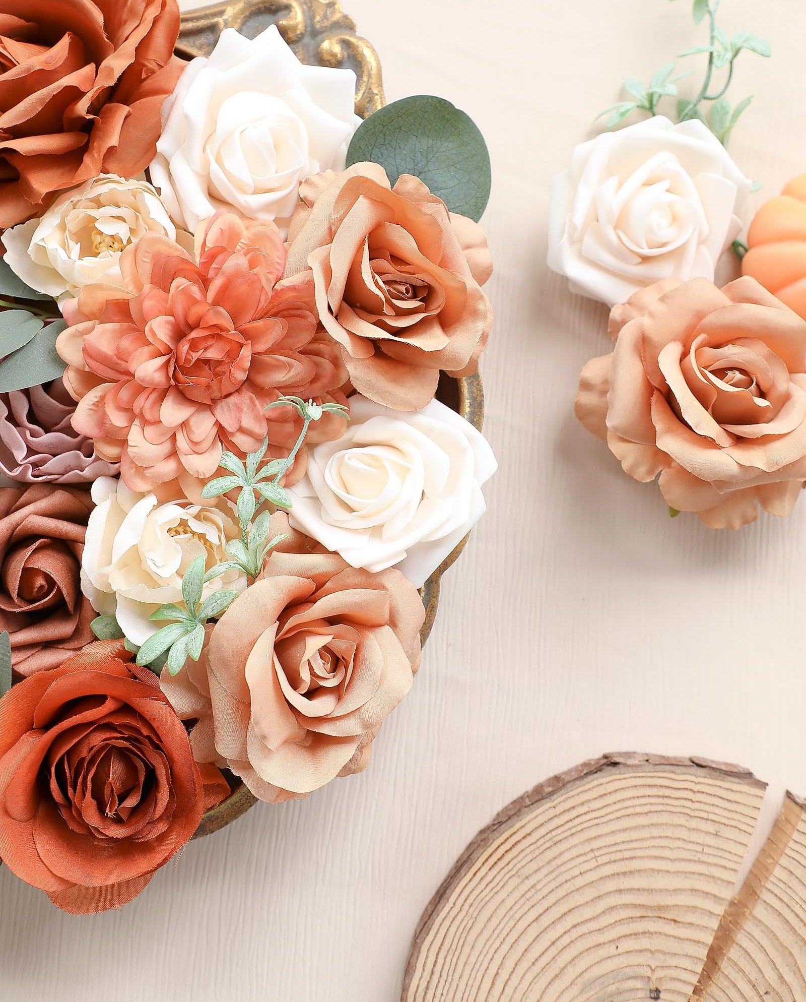 Assortment of artificial flowers in terracotta, champagne, amber, and cream colors arranged in a decorative gold tray.