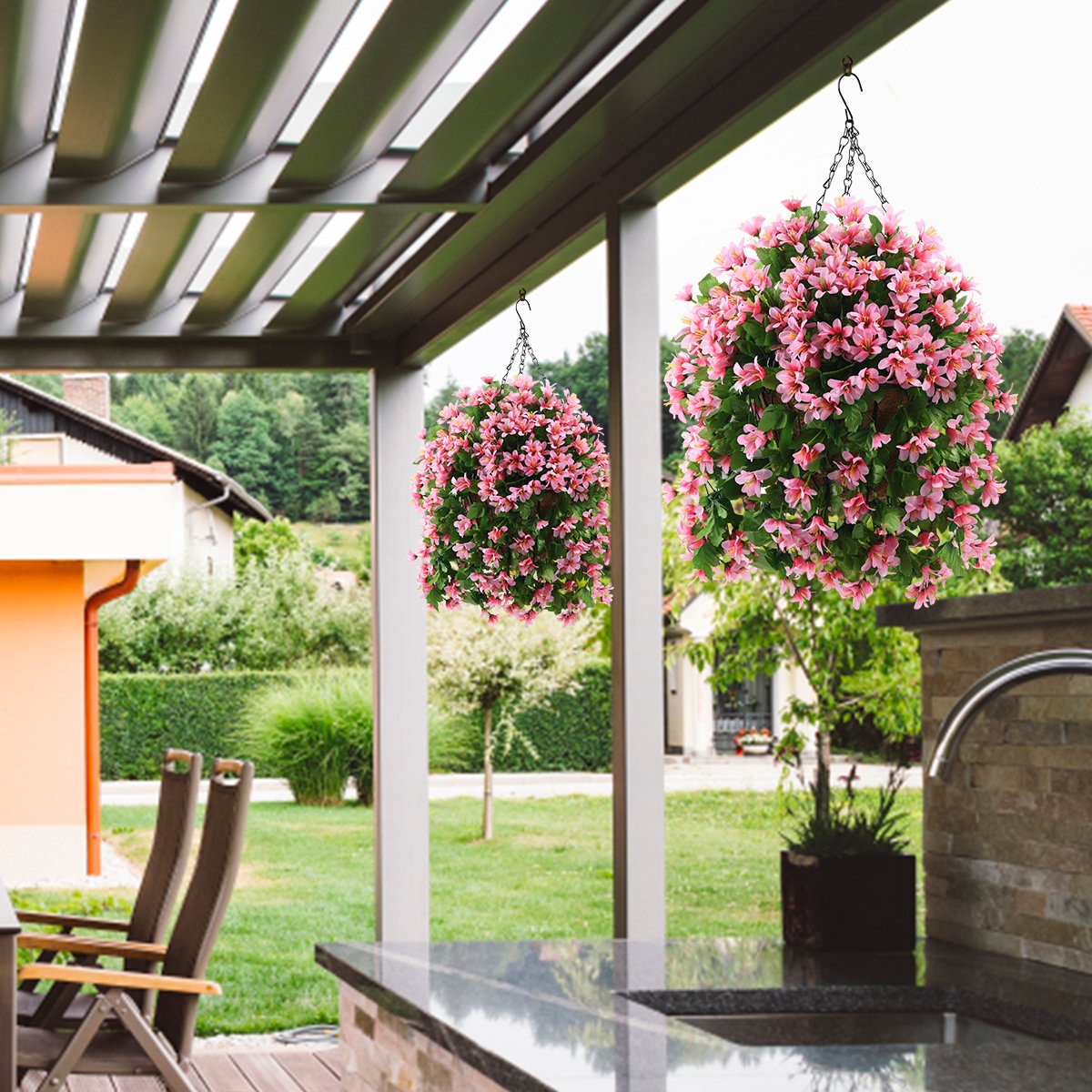 Two artificial hanging violet flower baskets with pink blossoms and green leaves, suspended from chains under a pergola.