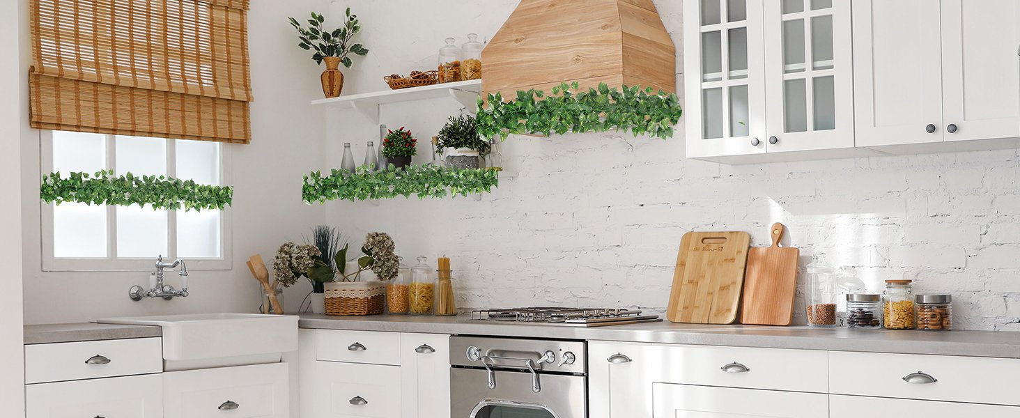 Artificial ivy vines draped across a kitchen window, shelf, and range hood, adding green decor.