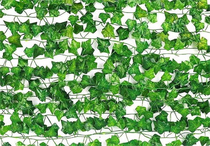 Artificial ivy vines with green silk leaves and plastic stems arranged horizontally on a white background.