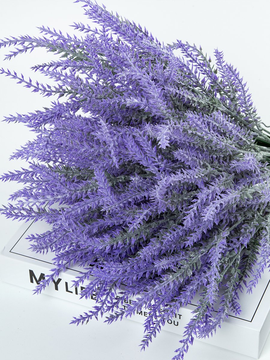 Close-up of artificial lavender bundles with purple flowers and green stems, resting on a book.