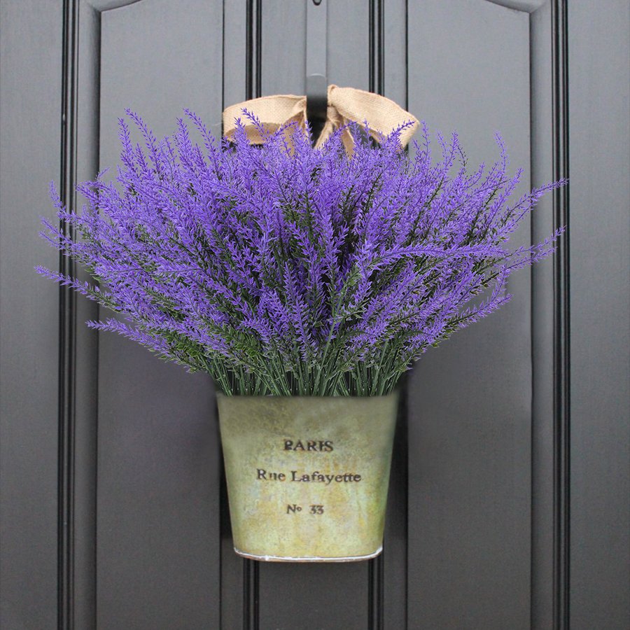 Artificial lavender bundles in a distressed pot hanging on a dark door, tied with a burlap bow.