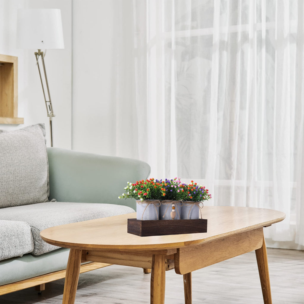 Artificial Milan flower centerpiece with three metal pots on a wooden tray, displayed on a coffee table.
