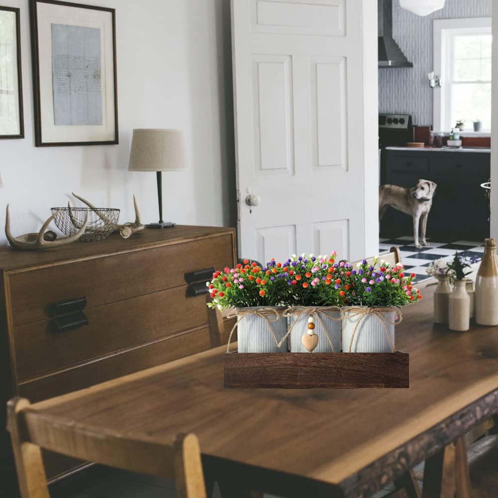 Artificial Milan flower centerpiece set with three metal pots on a wooden tray, displayed on a dining table.