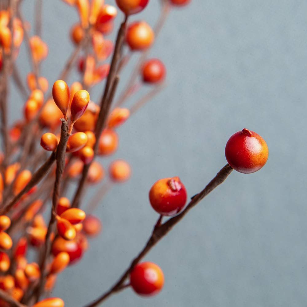 Close-up of artificial orange berry stems with a muted blue background.