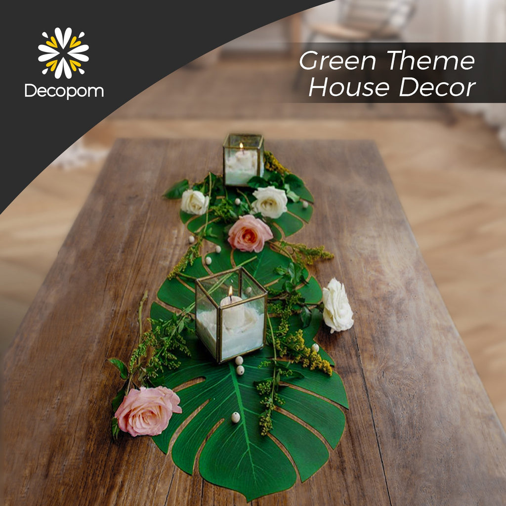 Table decorated with artificial palm leaves, roses, and candles in glass holders.