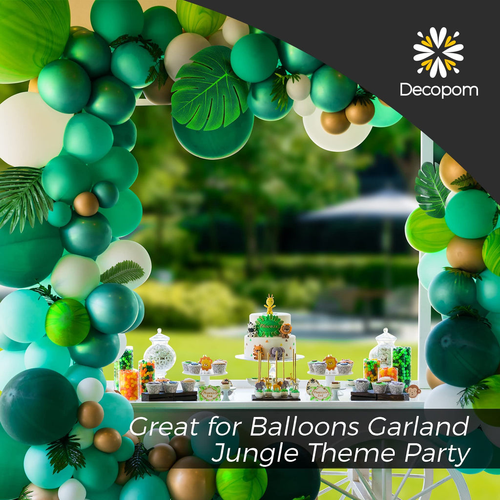 Jungle theme party setup with green balloons, cake, cupcakes, and candy jars, with a blurred outdoor background.