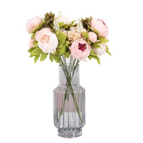 Light pink artificial peony bouquet with buds in a ribbed glass vase, isolated on white.