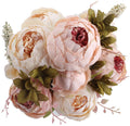 Light pink and cream artificial peony flower bouquet with buds and green leaves, top-down view.