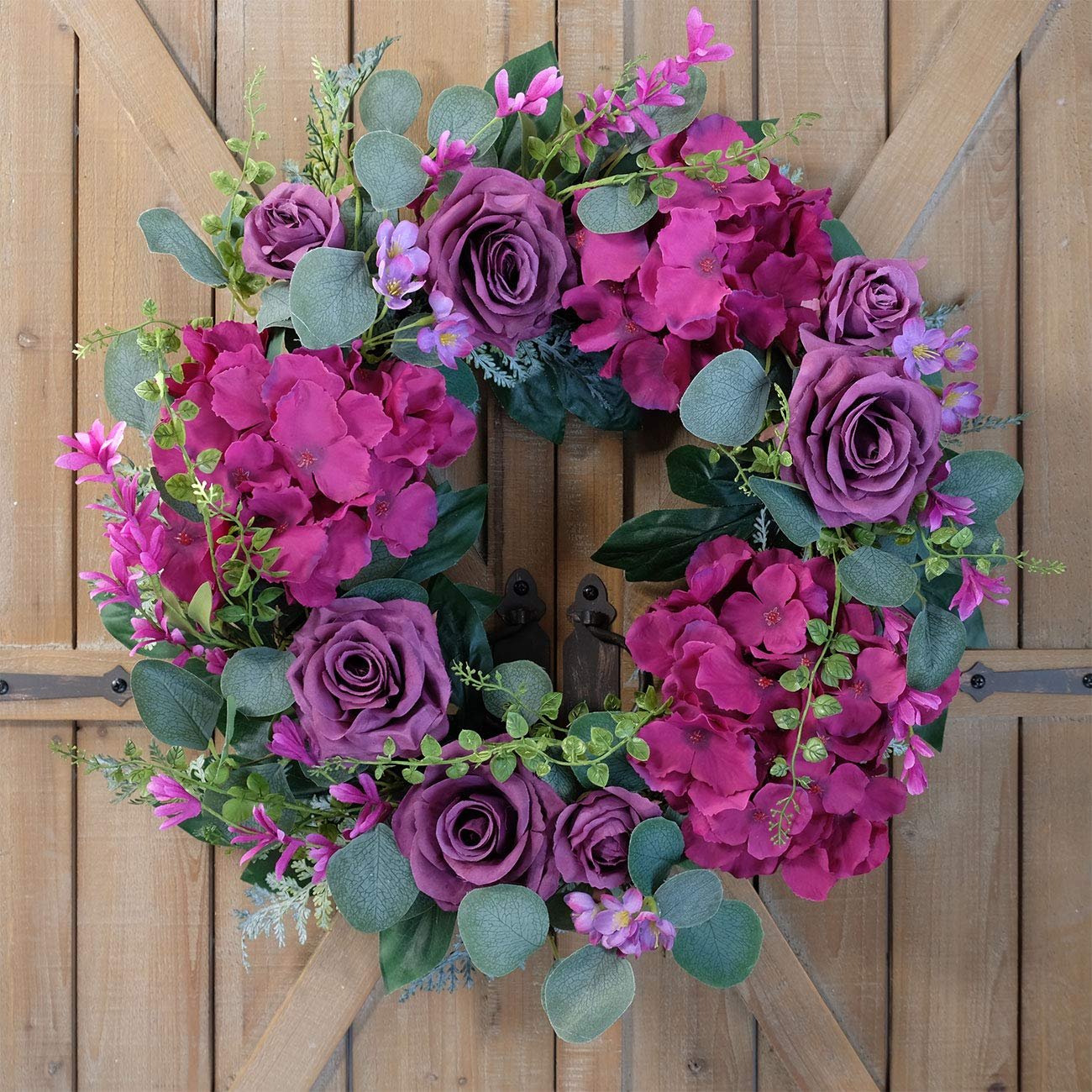 Purple rose and hydrangea artificial wreath with eucalyptus leaves on a wooden door