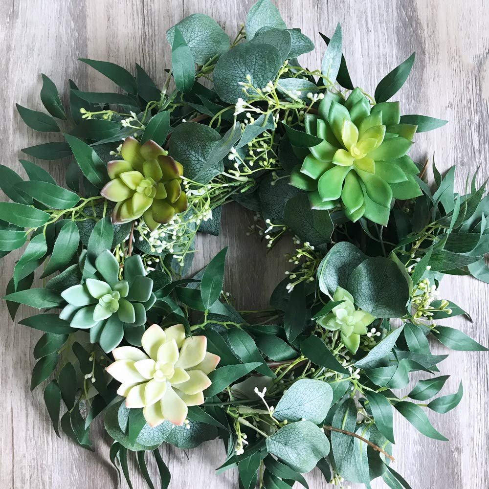Artificial succulent and eucalyptus garland arranged in a circular wreath shape on a wooden background.