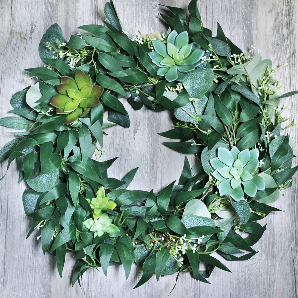 Artificial eucalyptus and succulent wreath on a wooden background, showing intertwined green leaves and faux succulents.
