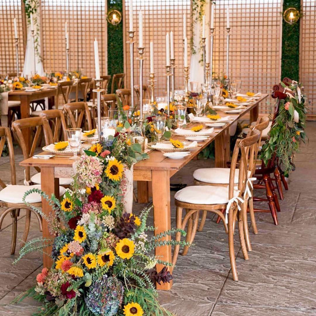 Wedding reception table setting with sunflowers, greenery, and candles