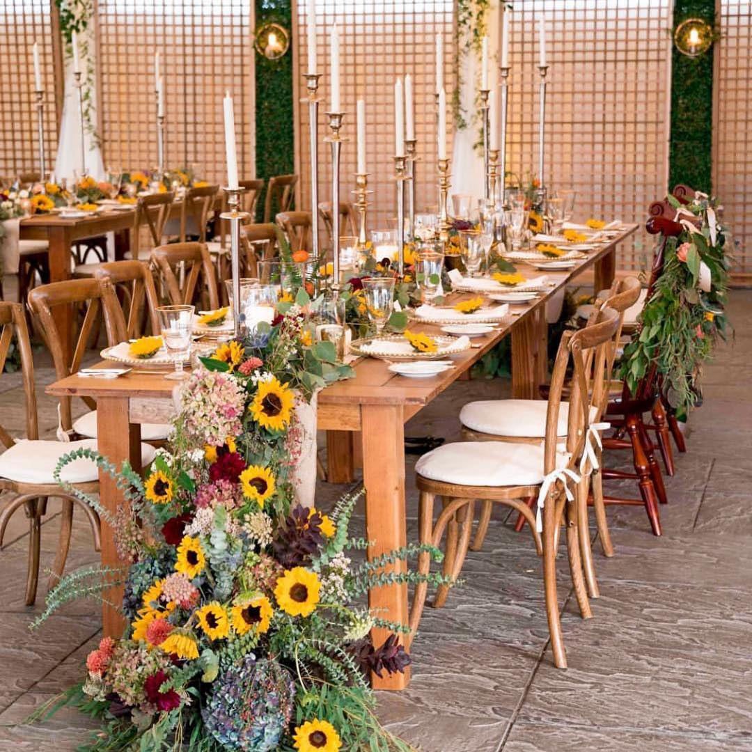 Wedding reception table setting with sunflowers, greenery, and candles
